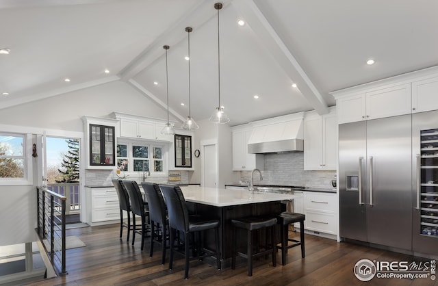 kitchen with a breakfast bar area, beam ceiling, tasteful backsplash, and stainless steel built in refrigerator