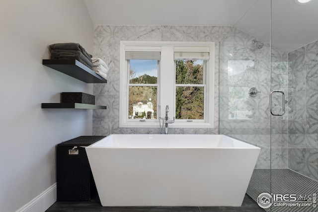 full bathroom featuring a freestanding tub, tile walls, a shower stall, and lofted ceiling