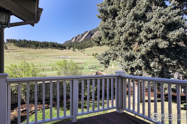 wooden deck with a mountain view, fence, and a rural view