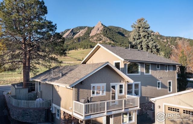 rear view of house with roof with shingles, a mountain view, and central air condition unit