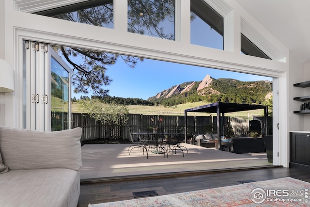 view of patio featuring a deck with mountain view, an outdoor living space, outdoor dining space, and a fenced backyard