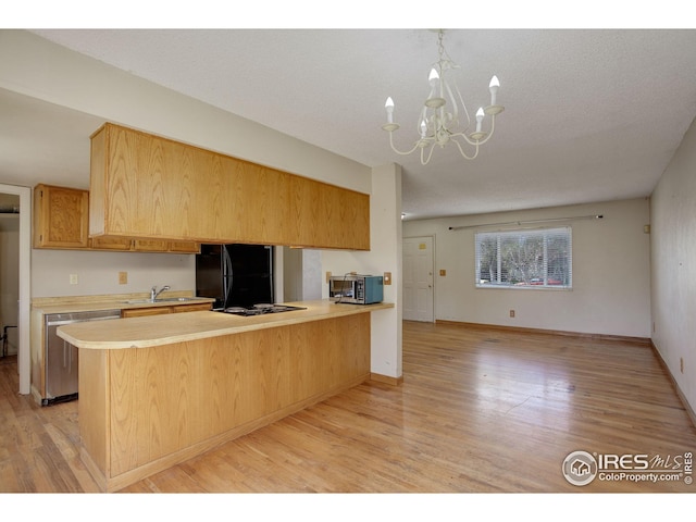 kitchen featuring light wood finished floors, light countertops, a chandelier, a peninsula, and black appliances
