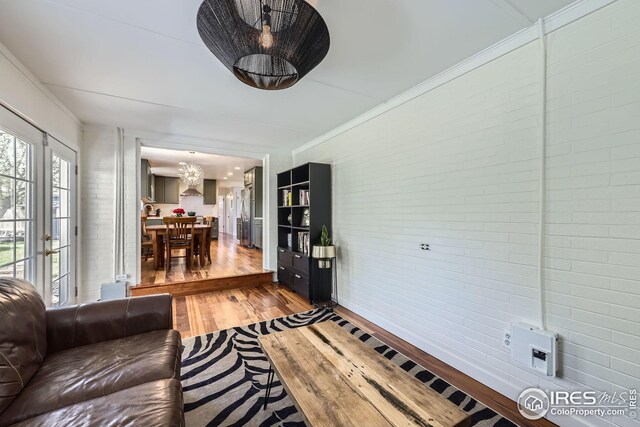 living area featuring brick wall, an inviting chandelier, and light wood-style floors