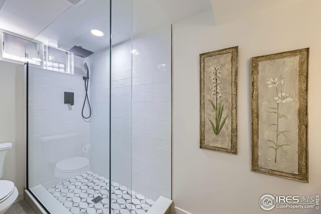 full bathroom featuring a tile shower and toilet