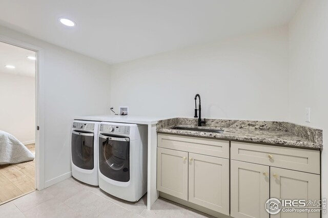 washroom with baseboards, recessed lighting, washer and clothes dryer, a sink, and cabinet space