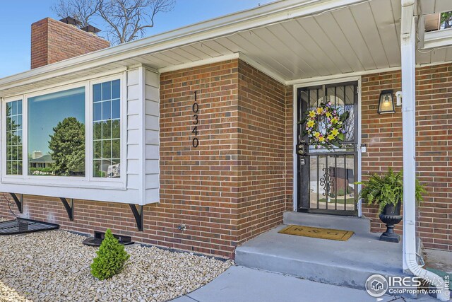 property entrance featuring brick siding and a chimney