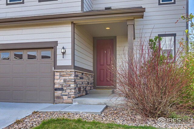 357 Chipman Dr, Windsor, CO 80550 - view of exterior entry with an attached garage and stone siding