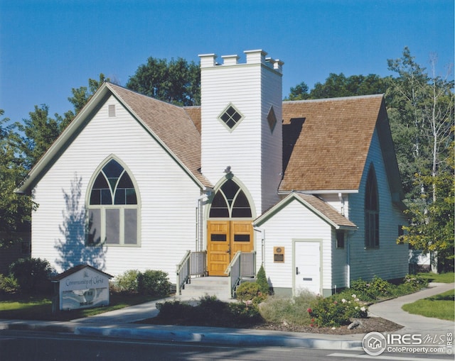 view of front of home with a shingled roof and a chimney