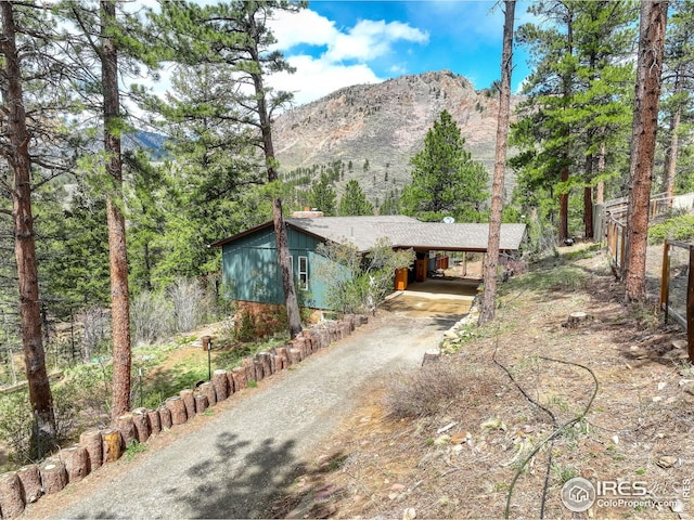 view of front facade with dirt driveway, a mountain view, and a carport