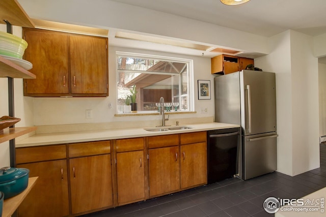 kitchen featuring dark tile patterned floors, a sink, light countertops, freestanding refrigerator, and black dishwasher