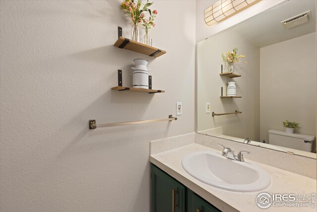 bathroom featuring vanity, toilet, and visible vents