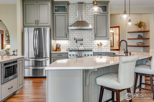 7628 Estate Cir, Niwot, CO 80503 - kitchen with backsplash, a sink, freestanding refrigerator, a breakfast bar, and wall chimney exhaust hood
