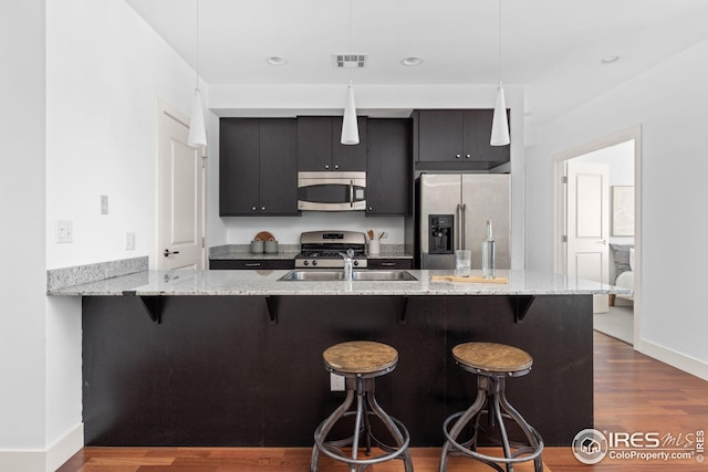 2001 Lincoln St Unit 2113, Denver, CO 80202 - kitchen with appliances with stainless steel finishes, a sink, a breakfast bar area, dark wood-type flooring, and a peninsula