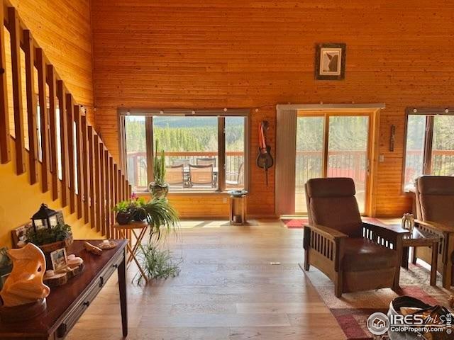 7127 Coal Creek Canyon Hwy, Nederland, CO 80466 - sitting room with wood finished floors, wood walls, a high ceiling, and stairs