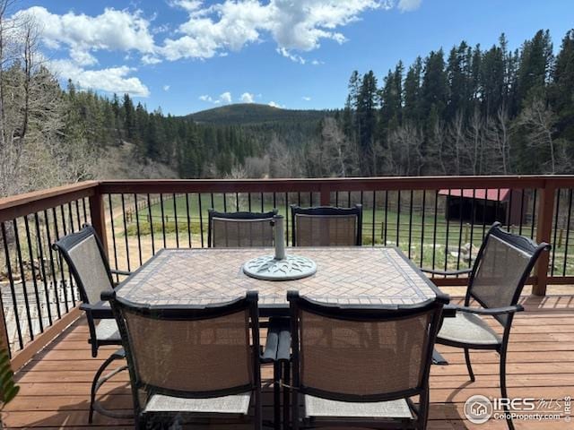 7127 Coal Creek Canyon Hwy, Nederland, CO 80466 - wooden terrace with outdoor dining space, a view of trees, and a mountain view