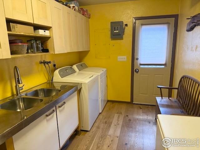 7127 Coal Creek Canyon Hwy, Nederland, CO 80466 - washroom featuring cabinet space, light wood-style floors, electric panel, and washer and dryer