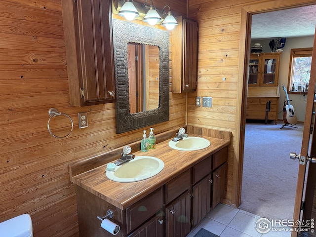 7127 Coal Creek Canyon Hwy, Nederland, CO 80466 - bathroom featuring double vanity, wood walls, tile patterned floors, and toilet