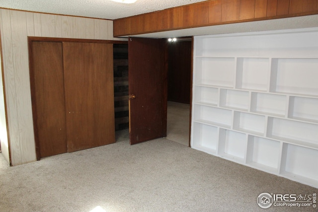 817 Warner St, Fort Morgan, CO 80701 - unfurnished bedroom featuring a textured ceiling, wooden walls, a closet, and carpet floors