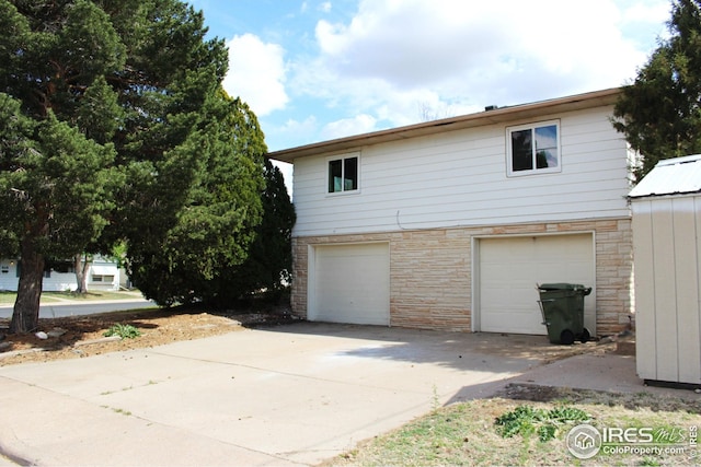 817 Warner St, Fort Morgan, CO 80701 - view of side of property featuring concrete driveway, stone siding, and a garage
