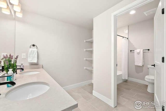 bathroom featuring a sink, double vanity, toilet, and baseboards