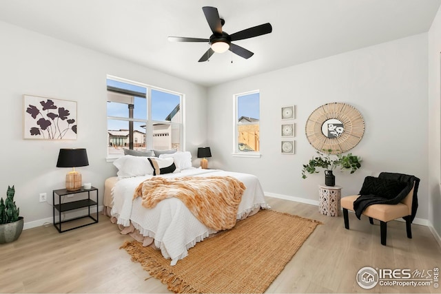 bedroom featuring baseboards, light wood-type flooring, and a ceiling fan