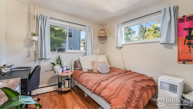 bedroom featuring baseboard heating and wood finished floors