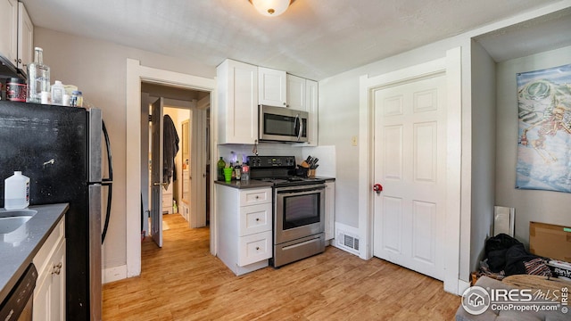 kitchen featuring appliances with stainless steel finishes, white cabinets, and light wood-style flooring