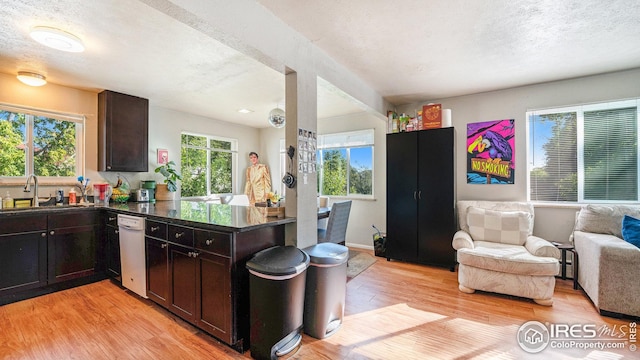 kitchen with a sink, light wood-style floors, open floor plan, a textured ceiling, and white dishwasher