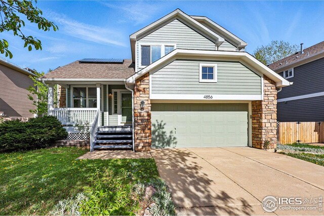 4856 10th St, Boulder, CO 80304 - view of front of property with roof mounted solar panels, covered porch, concrete driveway, an attached garage, and stone siding