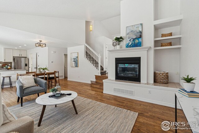 4856 10th St, Boulder, CO 80304 - living area with high vaulted ceiling, light wood-style flooring, stairway, a glass covered fireplace, and a chandelier