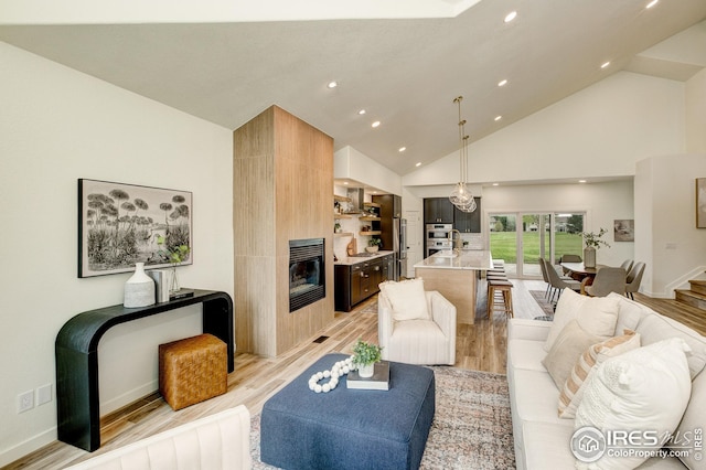 living room featuring a large fireplace, light wood finished floors, high vaulted ceiling, recessed lighting, and baseboards