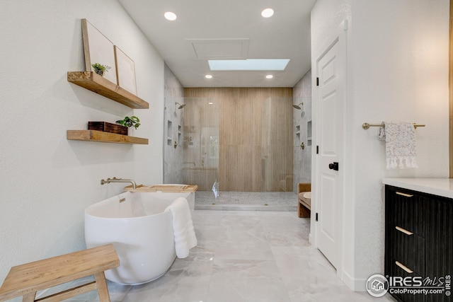bathroom with a stall shower, marble finish flooring, a soaking tub, and recessed lighting