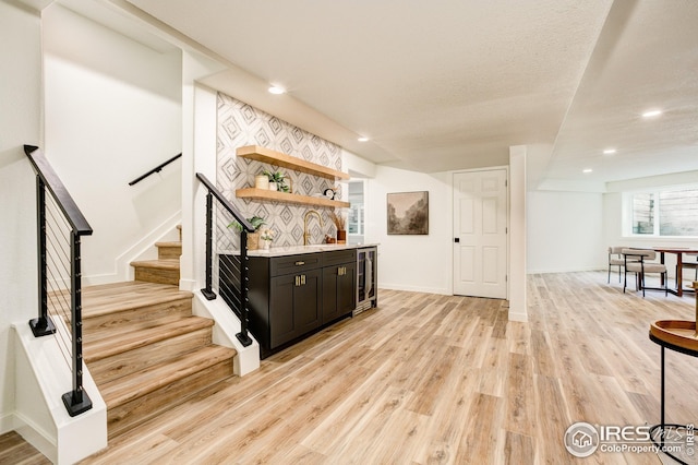 bar area featuring light wood-type flooring, stairway, recessed lighting, beverage cooler, and baseboards