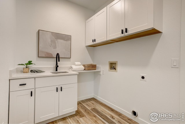 laundry room with hookup for a washing machine, light wood-style floors, baseboards, and cabinet space