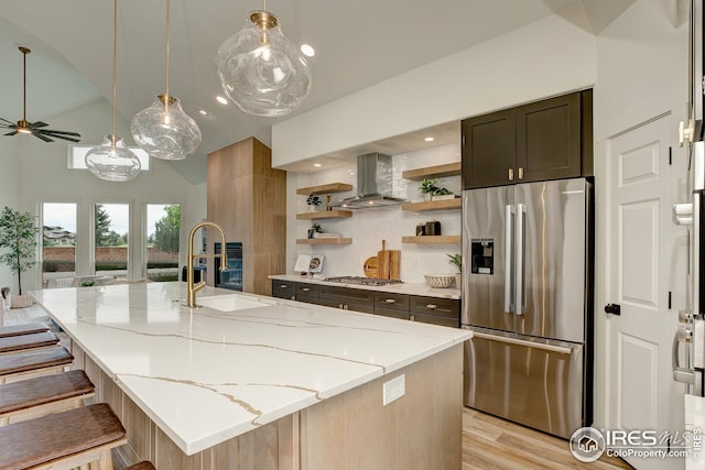 kitchen with appliances with stainless steel finishes, wall chimney range hood, lofted ceiling, light stone counters, and open shelves
