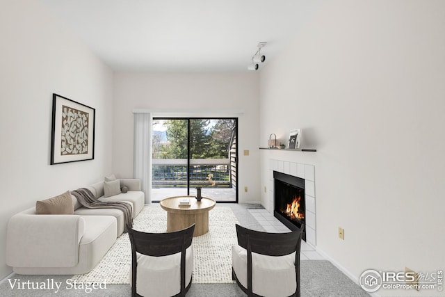 living area with a tile fireplace, rail lighting, and baseboards