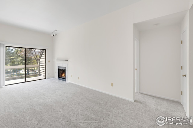 unfurnished living room featuring carpet, a tile fireplace, and baseboards