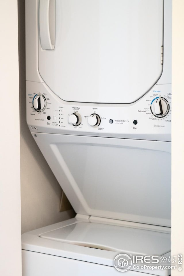 clothes washing area featuring stacked washer and clothes dryer