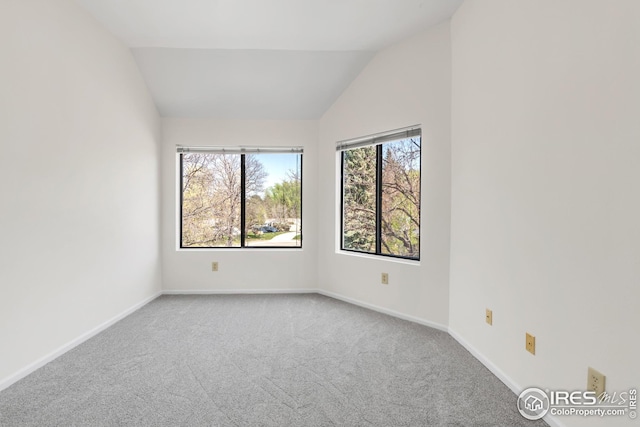 carpeted empty room with lofted ceiling and baseboards