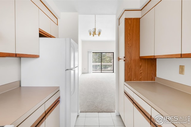 kitchen with light colored carpet, light countertops, a chandelier, white cabinetry, and freestanding refrigerator