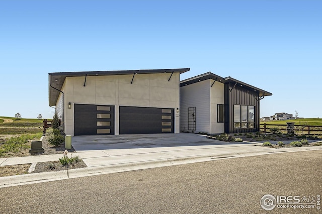 contemporary house featuring a garage, concrete driveway, and fence