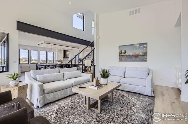living area featuring stairs, wood finished floors, a high ceiling, and baseboards