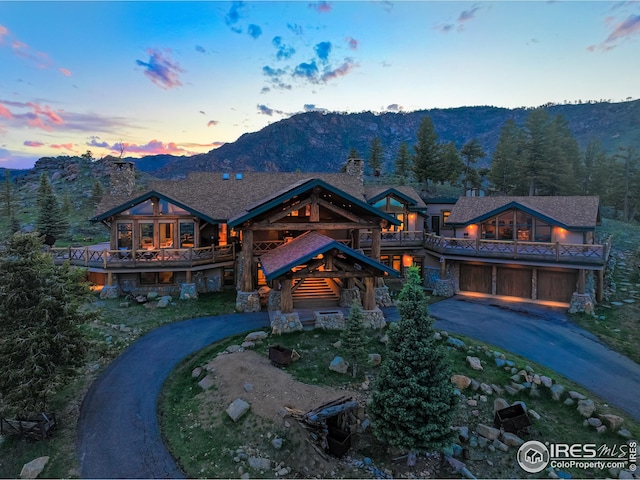 log cabin featuring curved driveway, a chimney, a mountain view, an attached garage, and a balcony
