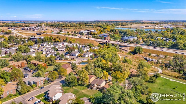 aerial overview of property's location with a nearby body of water, nearby suburban area, and a tree filled landscape