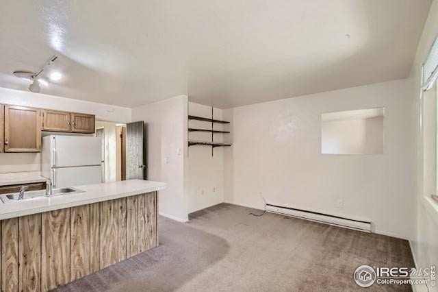 kitchen featuring freestanding refrigerator, baseboard heating, a sink, carpet flooring, and track lighting