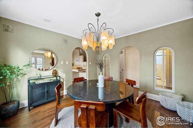 229 Albion St, Denver, CO 80220 - dining area featuring arched walkways, dark wood-style floors, a chandelier, crown molding, and baseboards