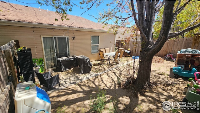 rear view of property featuring a fenced backyard, a patio area, and roof with shingles