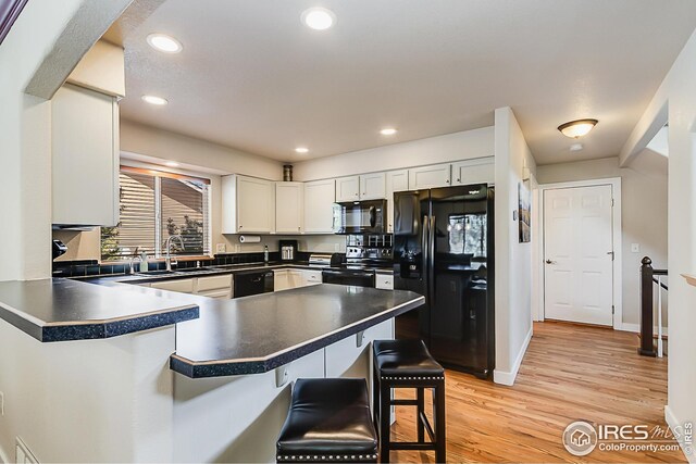 1108 Basin Ct, Windsor, CO 80550 - kitchen with black appliances, a sink, dark countertops, a breakfast bar area, and a peninsula