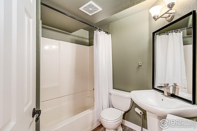 1108 Basin Ct, Windsor, CO 80550 - bathroom featuring a textured wall, toilet, shower / tub combo, a sink, and wood finished floors