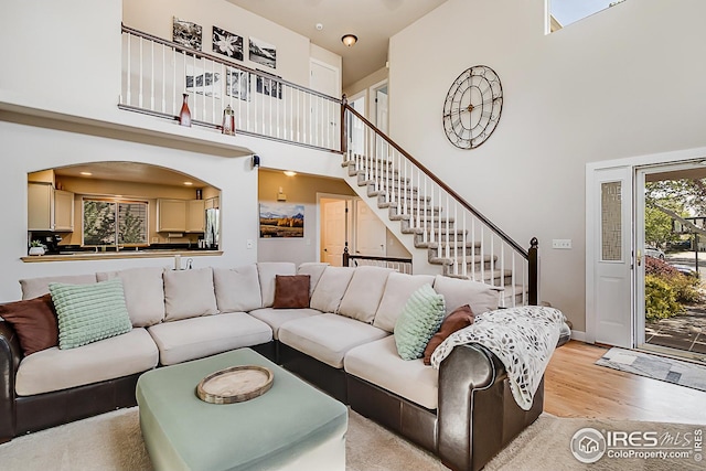1108 Basin Ct, Windsor, CO 80550 - living area featuring a high ceiling, stairs, light wood-style floors, baseboards, and arched walkways